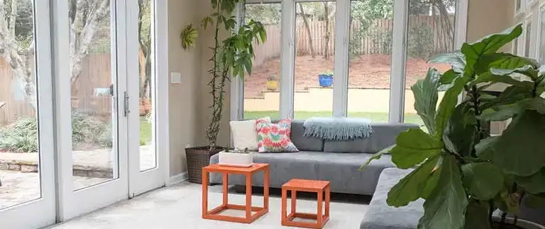 Sunroom construction, bright finished sunroom with large windows, plants, and modern seating