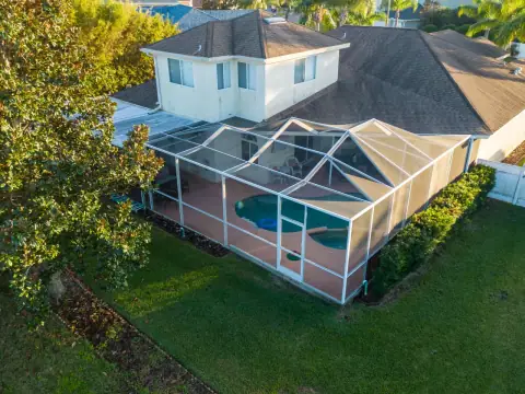Aerial view of a pool screen enclosure surrounded by landscaping