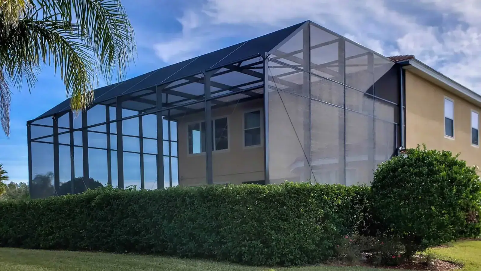 Aluminum pool cage enclosure over a backyard swimming pool