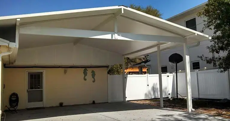 Attached aluminum carport covering a driveway beside a single-story Florida house