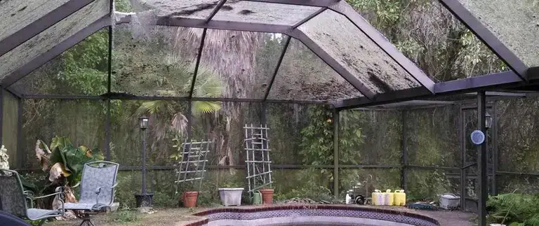 Torn and sagging screen panels on a damaged pool cage in Central Florida