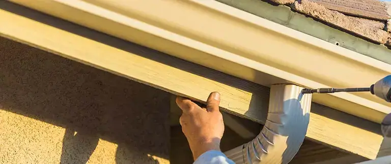 Installer hanging a new seamless aluminum gutter on a Central Florida home