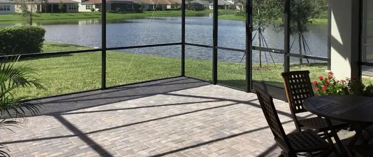 Paver patio under a lanai beside a lake