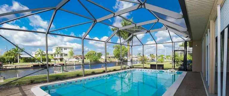 Aluminum pool cage framing under construction showing posts, beams, and anchors