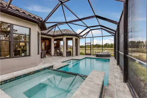 Pool cage enclosure with aluminum framing around a backyard pool